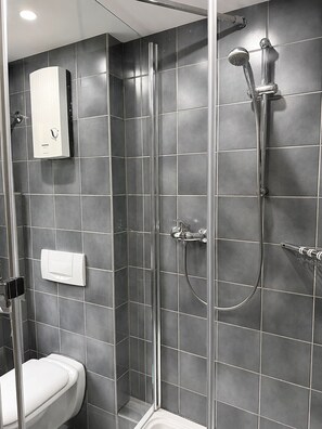 A modern bathroom with a glass-enclosed shower, a toilet, and a towel rack.