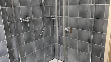 Eine moderne Duschkabine mit Glastür, Handbrause und am Wand montiertem Wasserhahn.