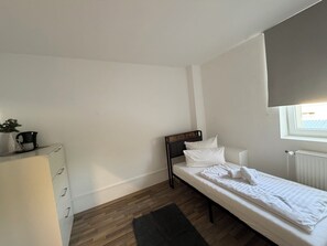 A small, clean room with a single bed, a dresser, and a window with a view.