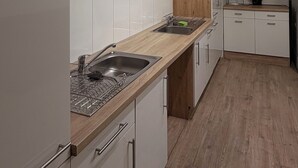 A modern kitchen with white cabinetry, a wooden countertop, and a built-in oven.