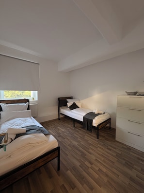 A bedroom with two beds, a dresser, and a window. - Europension - Ettlingen (Ettlingen)