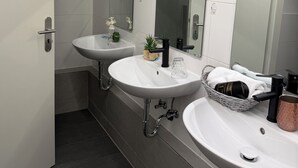 A modern bathroom with two sinks, a mirror, and a towel rack.