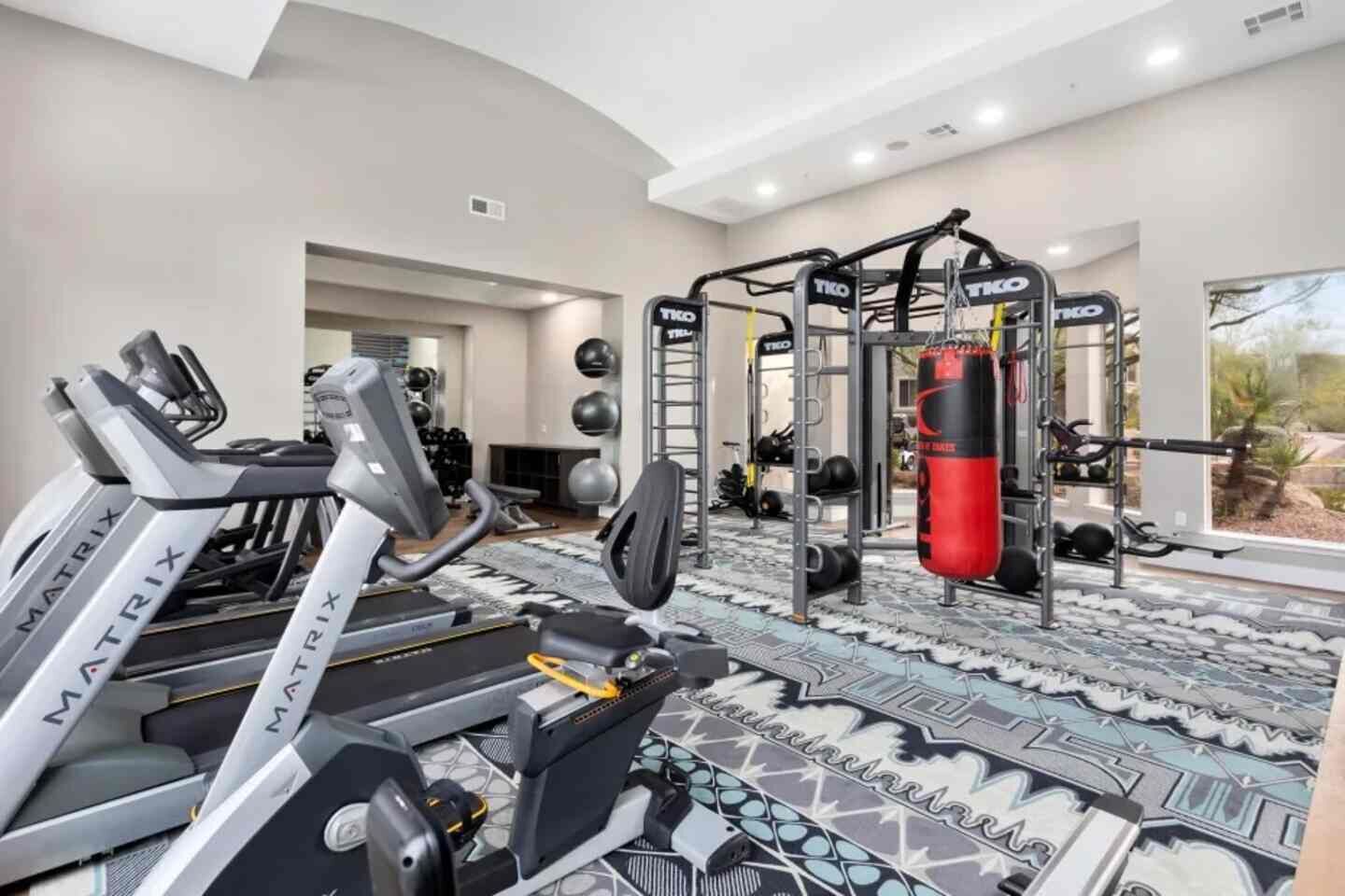 Ein Fitnessraum mit Laufbändern, einer Klimmzugstange und einem Schlagbeutel.