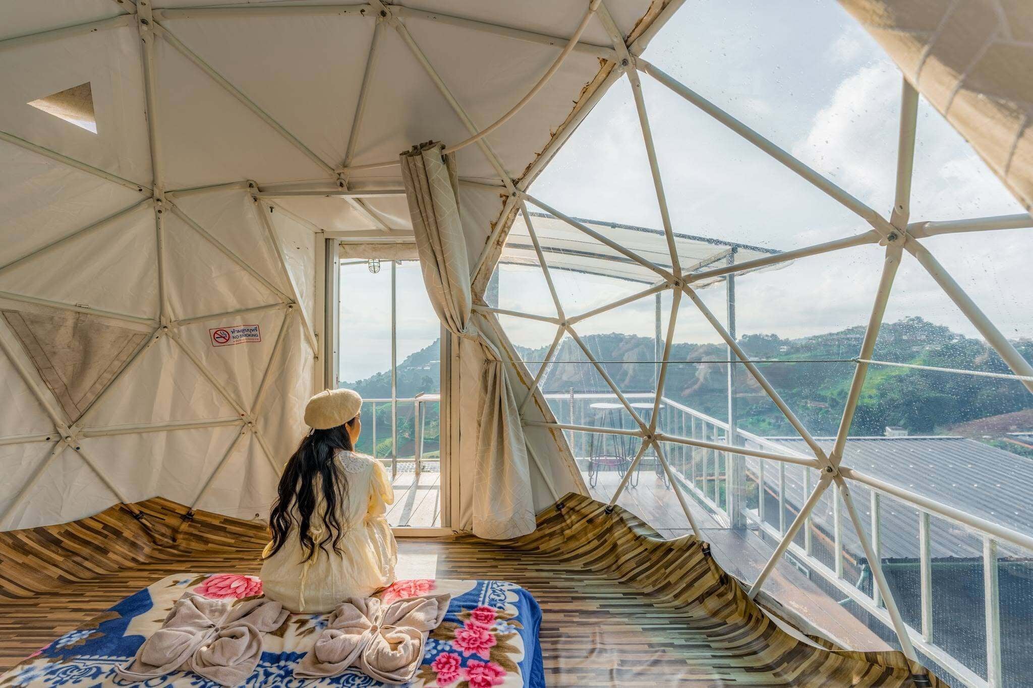 Habitación con tienda de campaña, una cama y vista a un puente, con un cartel que indica prohibido fumar.
