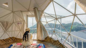 Habitación con tienda de campaña, una cama y vista a un puente, con un cartel que indica prohibido fumar.