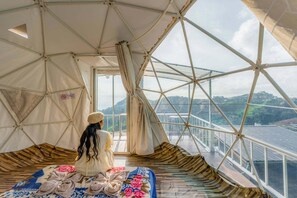 Quarto com tenda, uma cama e vista para uma ponte, com placa indicando que não é permitido fumar.