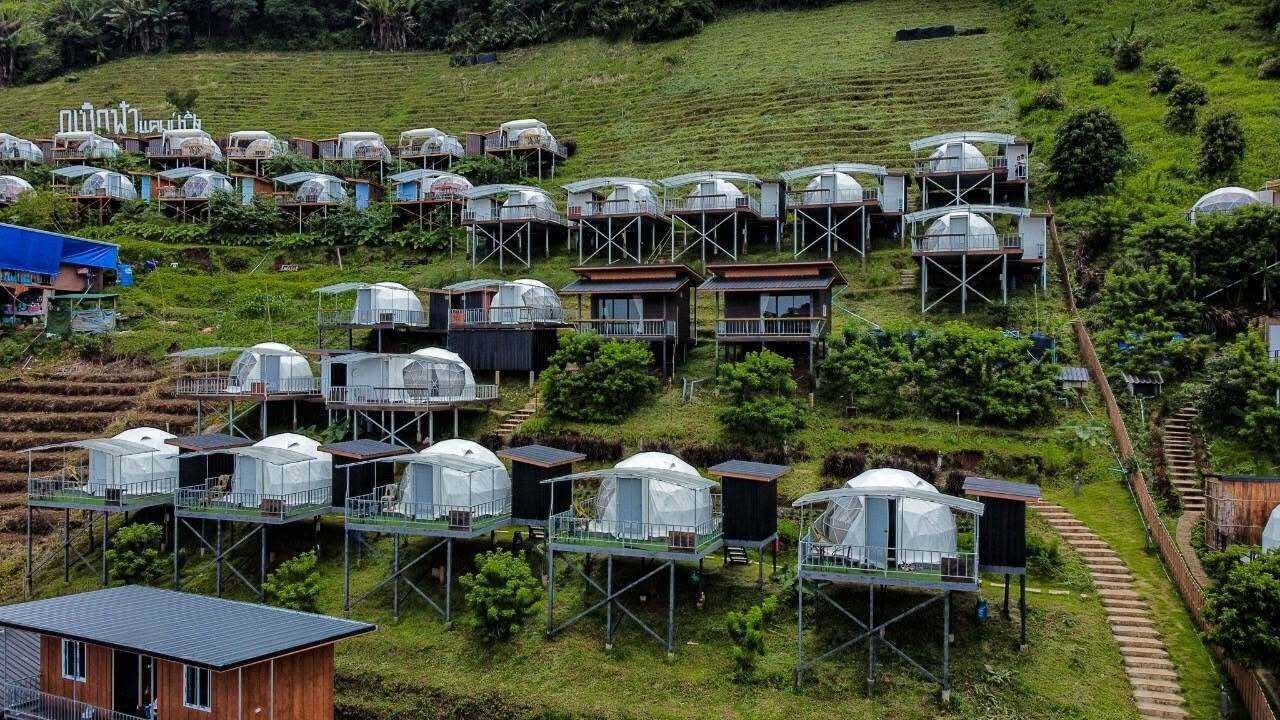 A cluster of dome-shaped accommodations on stilts, surrounded by terraced fields.