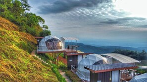 Um imóvel numa encosta com várias estruturas em formato de cúpula, cada uma com varanda e vista para a paisagem circundante.