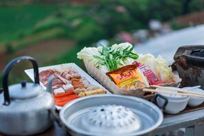 Uma mesa com diversos alimentos, uma chaleira e um fogão portátil.