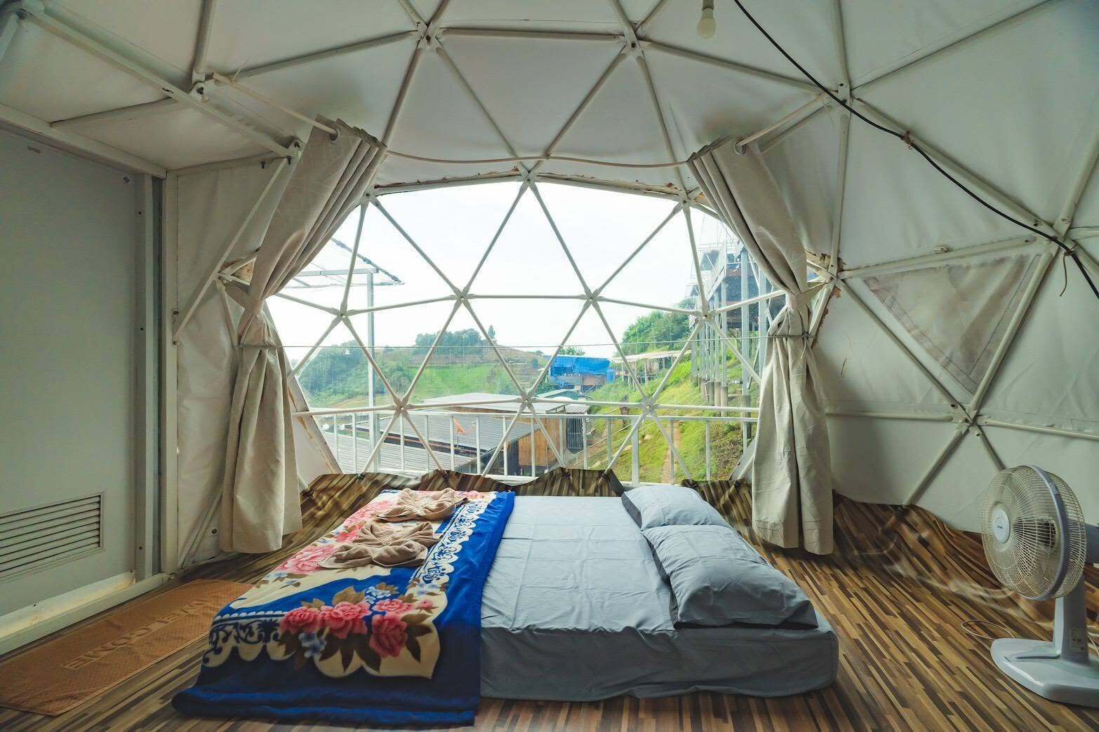 A tent-style room with a bed, curtains, and a fan.