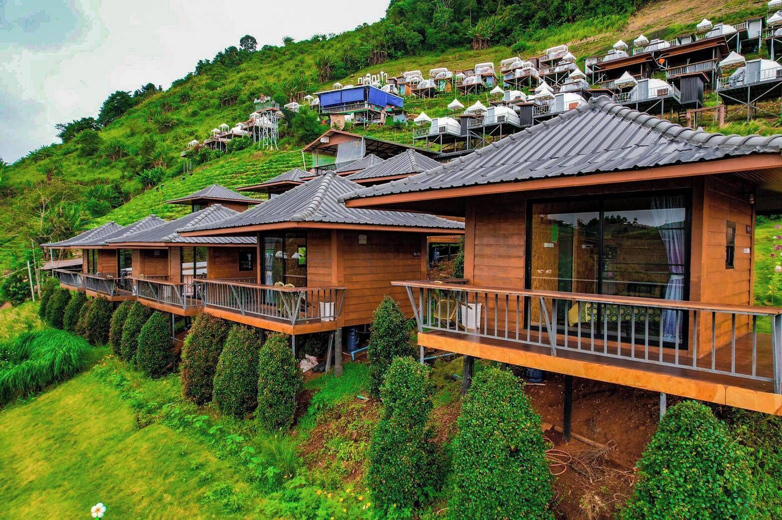 A hillside property with multiple wooden cabins featuring balconies and large windows.