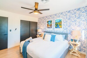 Ein Schlafzimmer mit einem Bett, zwei Nachttischen, einem Deckenventilator und einer Tür.