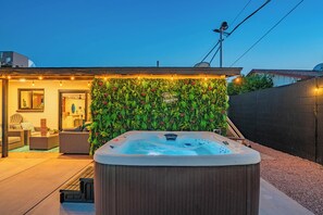 Un bain à remous dans un jardin, avec un mur végétal et un espace patio aménagé avec des sièges.