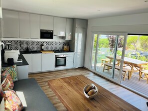 A modern kitchen with white cabinets, a built-in oven, and a coffee machine. - Sun, sea, and Lisbon—your vacation home is waiting for you (Costa de Caparica)