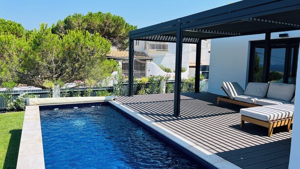 A swimming pool with a wooden deck and lounge chairs. - Sun, sea, and Lisbon—your vacation home is waiting for you (Costa de Caparica)
