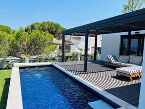A swimming pool with a wooden deck and lounge chairs. - Sun, sea, and Lisbon—your vacation home is waiting for you (Costa de Caparica)