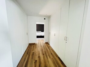 A corridor with wooden flooring leading to a bedroom with a bed and a wardrobe. - Sun, sea, and Lisbon—your vacation home is waiting for you (Costa de Caparica)