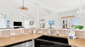 A modern kitchen with a dishwasher, a sink, and a ceiling fan. - 🏄🌴Golf Cart | Steps to Beach | Multiple Balconies | Pelican Pod☀️ (Navarre)