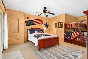 Quarto com cama beliche de madeira, ventilador de teto e decoração com bandeiras dos Estados Unidos.