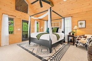 Ein hölzernes Zimmer mit Himmelbett, einem gemusterten Teppich und einem Sofa mit Kuhmuster.