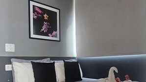 Ein Schlafzimmer mit einem Bett, Kissen, einer Decke, einer Klimaanlage und einem gerahmten Bild an der Wand.