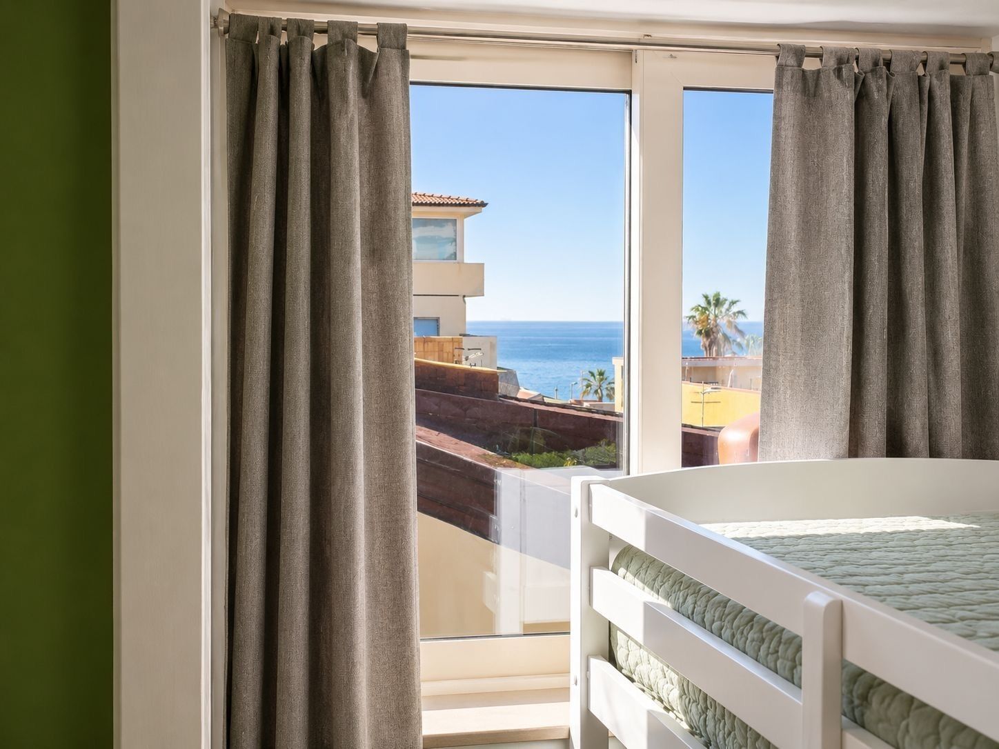 Ein Zimmer mit Bett, einem fenster mit Vorhängen und Meerblick.