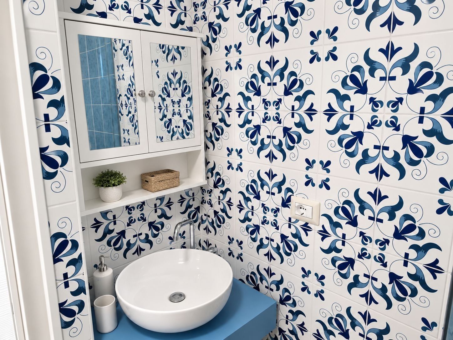 Un bagno con un lavandino bianco, un piano di lavoro blu e piastrelle decorative.