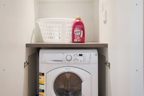 A laundry area with a washing machine and a basket on top of it. - Amyra Residences on Rowlands Place - Unit 605 (Adelaide)