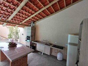 Una cocina con mostrador de ladrillo, un fregadero, armarios, estufa y refrigerador.