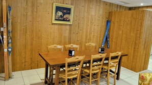 A wooden-paneled room with a dining table and chairs, a framed picture on the wall, and skis leaning against the wall. - ABRIES HOTEL  (Abriès-Ristolas)