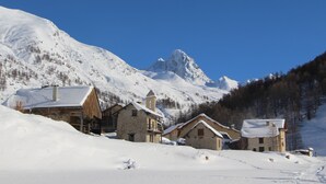 A snow-covered mountain village with traditional wooden houses and a clear blue sky. - ABRIES HOTEL  (Abriès-Ristolas)