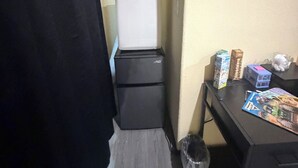 Ein gemütlicher Raum mit Kühlschrank, einem kleinen Tisch mit Gegenständen und einem Mülleimer.