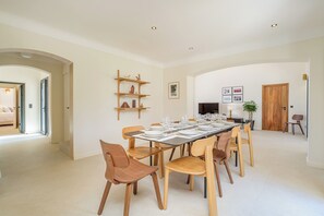 A dining area with a long table set for six, surrounded by wooden chairs. - Villa Eméa |Pool, gym & pétanque court (Le Puy-Sainte-Réparade)