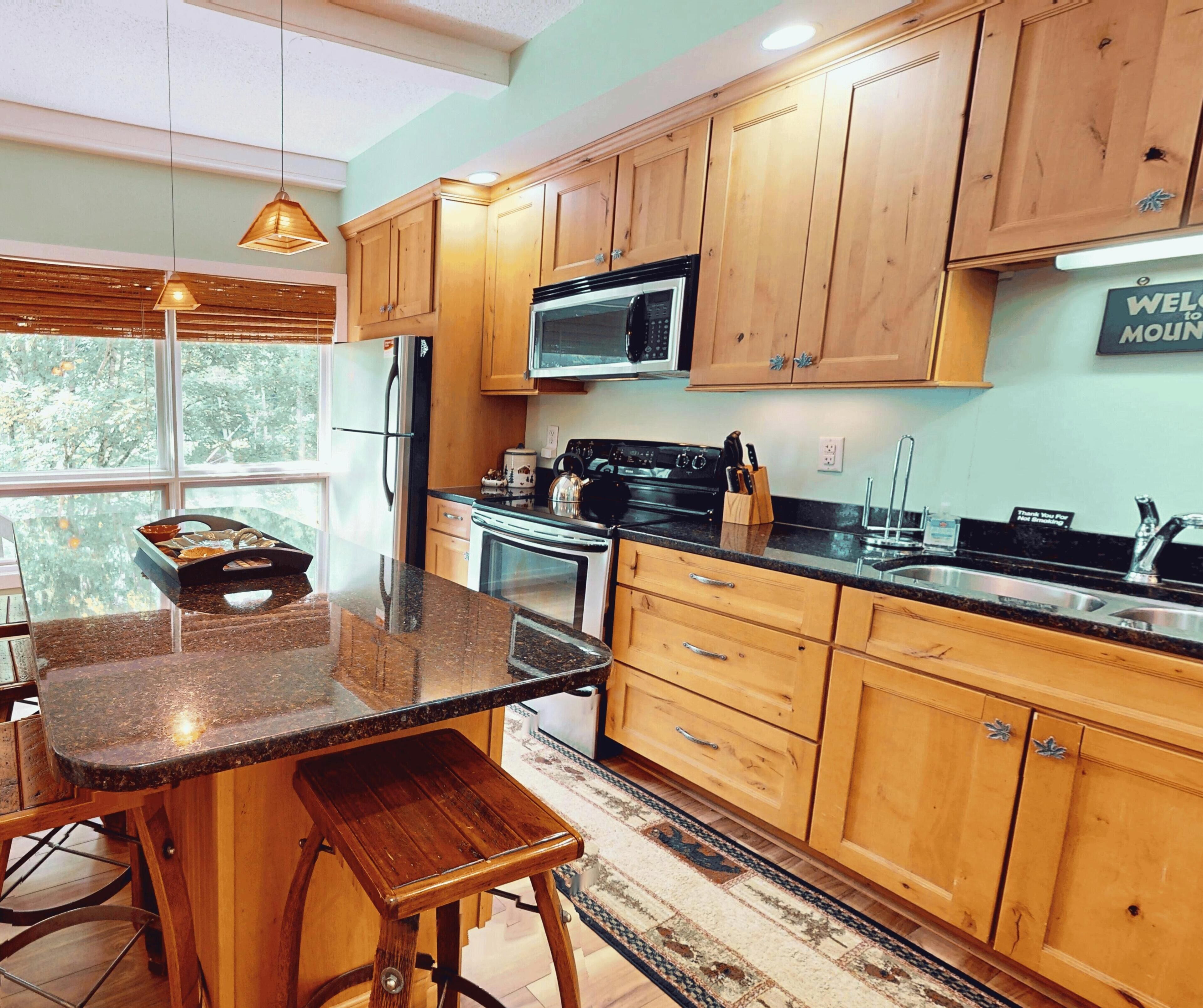 A modern kitchen with wooden cabinets, a stainless steel refrigerator, a microwave, and a gas stove.
