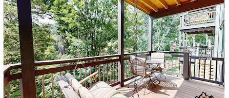 A covered balcony overlooks lush greenery, with a swing offering the perfect spot to unwind while surrounded by peaceful mountain trees and fresh air.