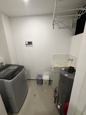 Ein kleines Badezimmer mit Waschmaschine, Toilette, Waschbecken und Warmwasserbereiter.
