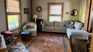 A living room with a sofa, armchair, ottoman, and a patterned rug. - Little League Getaway - Sleeps 10 - Spacious 4-bedroom, mins from stadium (Williamsport)