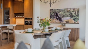 Un comedor moderno con una mesa redonda, sillas blancas y una lámpara de araña.