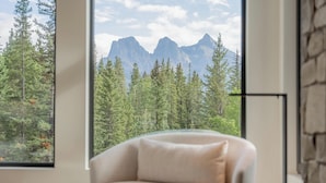 Una habitación con un ventanal que ofrece vistas a un bosque y montañas.
