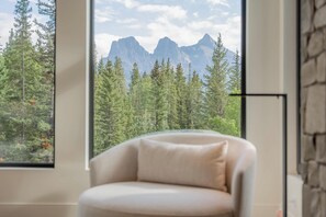 A room with a large window offering a view of a forest and mountains.