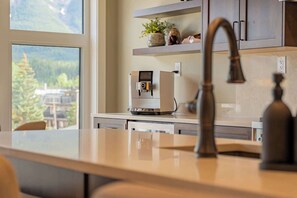 Une cuisine au design moderne, dotée d’une machine à café et offrant une vue sur l’extérieur.
