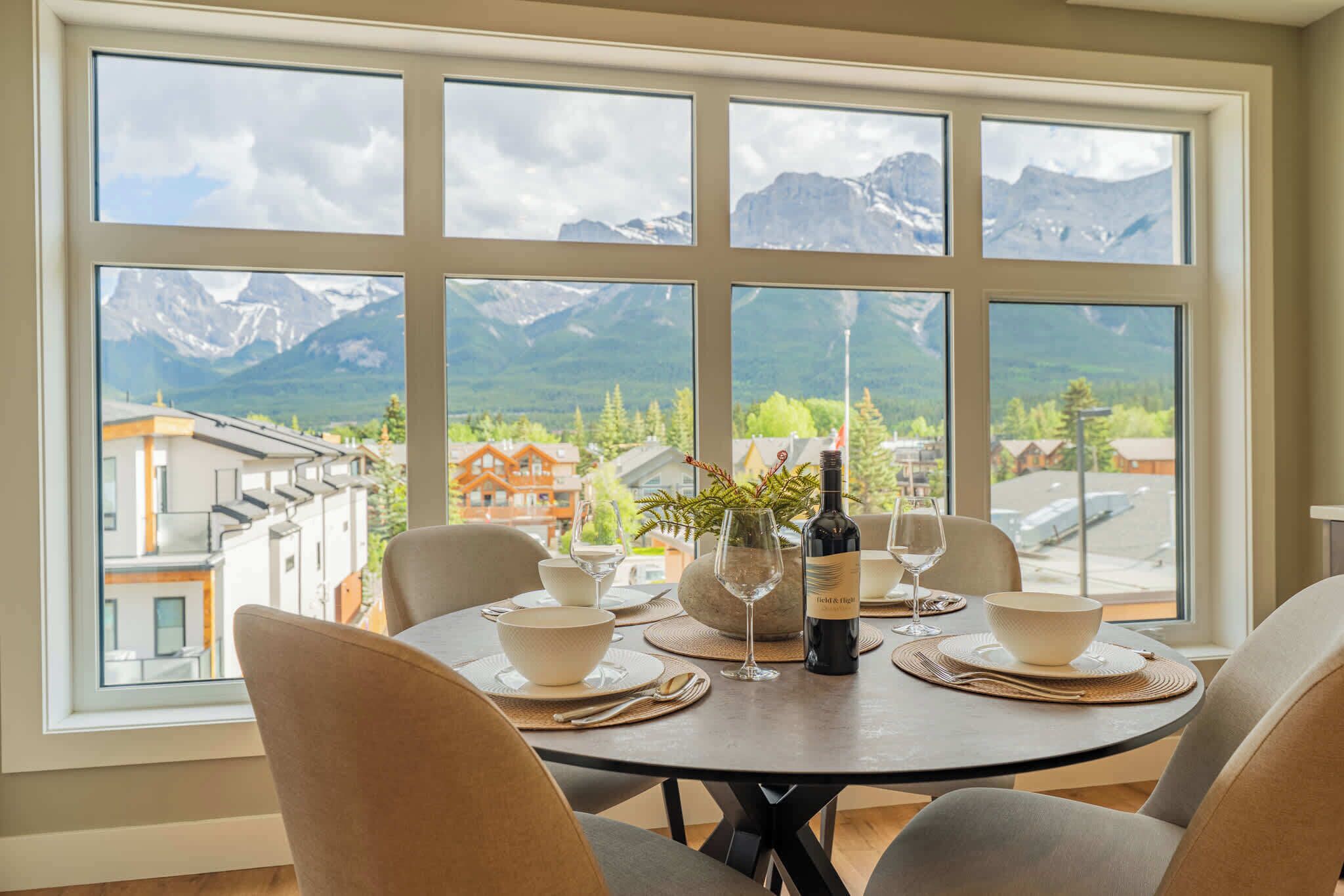 Ein Esstisch für vier Personen mit Blick auf die Berge durch große Fenster.