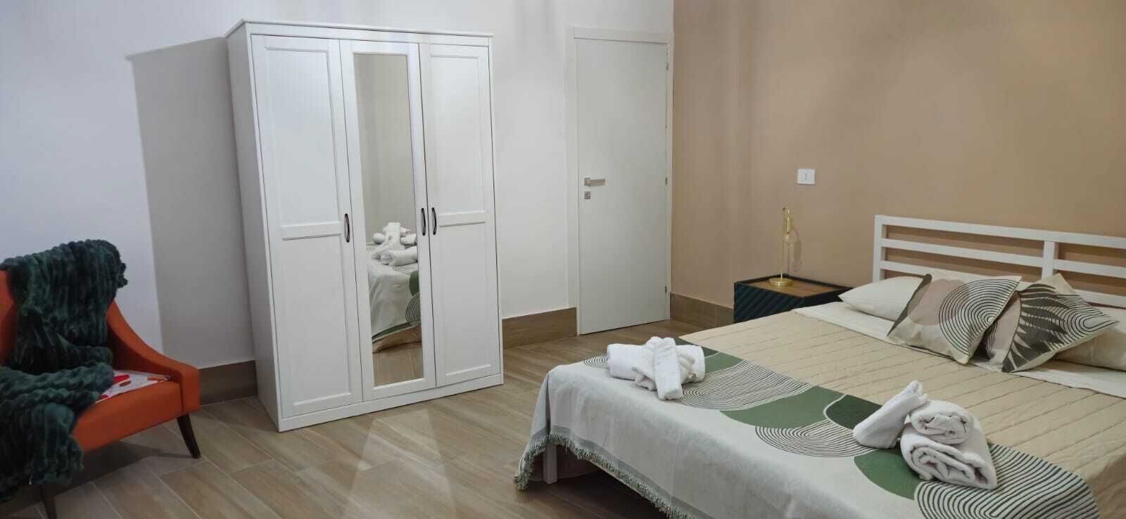 A bedroom with a bed, a wardrobe, a chair, and a nightstand.