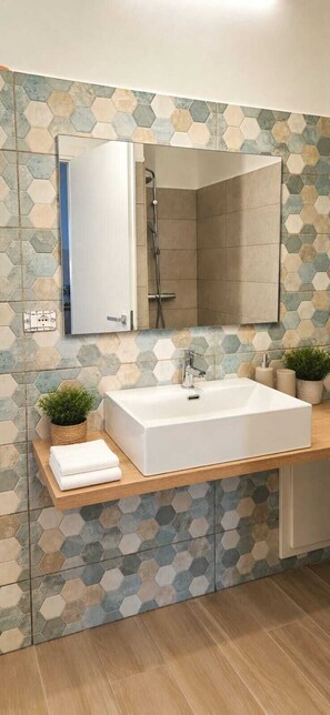 A bathroom with a large rectangular sink, a mirror above it, and a shower area. - Sambè Apartment—Your Stay in the Heart of Catania (Catania)