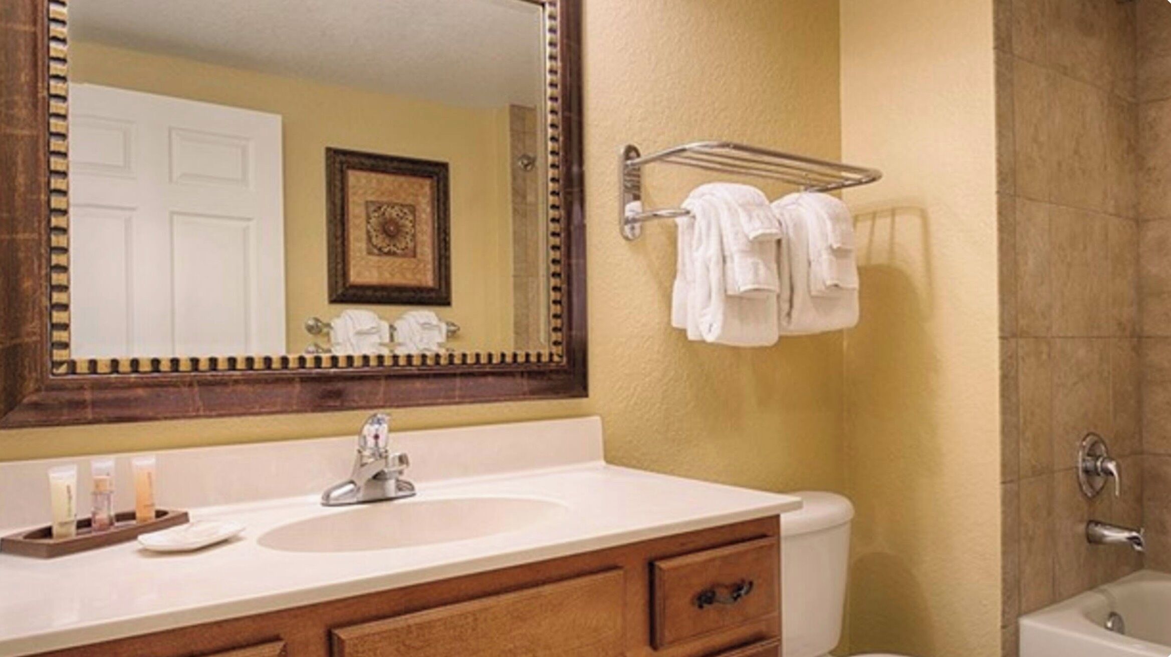 Une salle de bain équipée d’un lavabo, d’un miroir, d’un porte-serviettes et d’un espace douche.