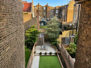 A courtyard with a lawn, a table and chairs, and a shed. - Notting Hill's Iconic Pink House Mid / Long term (London)