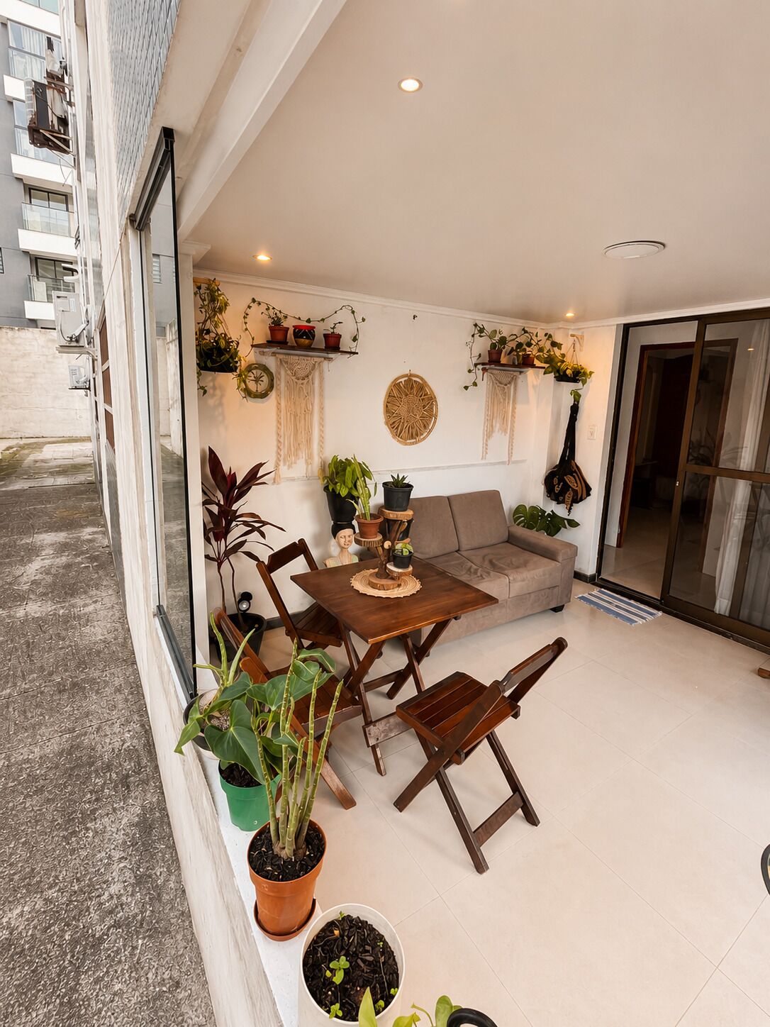 Un espacio habitable de concepto abierto con sofá, mesa de comedor y sillas, rodeado de plantas en macetas y objetos decorativos.