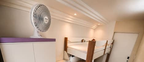 A bunk bed with a white wardrobe and a ceiling fan in a room with a tiled floor.