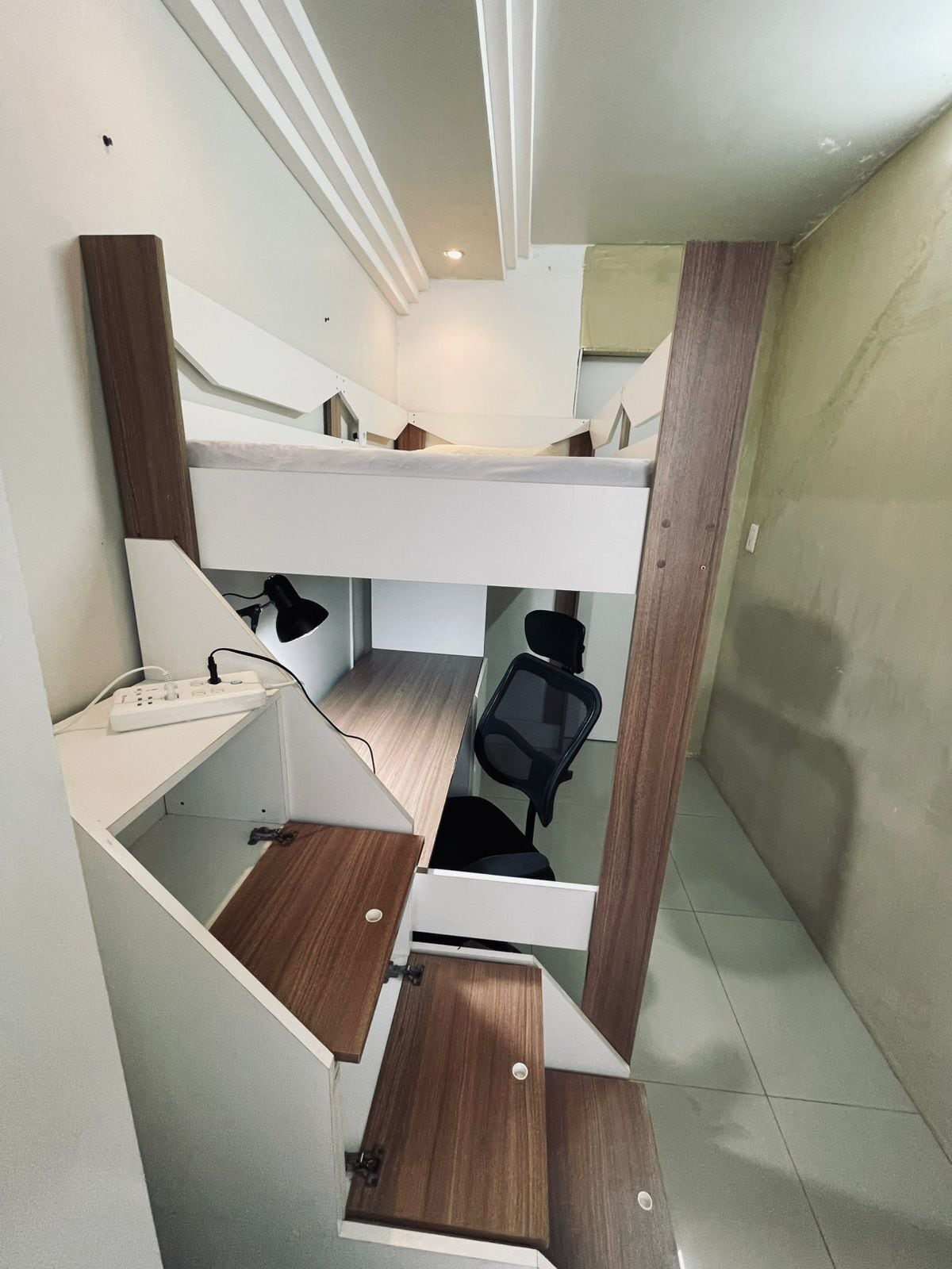 Ein kleines Zimmer mit Etagenbett, Schreibtisch und Stuhl.