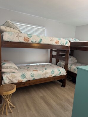 Ein Etagenbett mit floraler Bettwäsche, ein Holzstuhl und ein kleiner Tisch in einem Zimmer mit Holzboden.